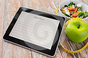 Close up of diet plan on tablet pc and food