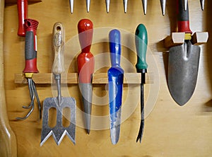 Close up of different gardening tools hanging on the wall in a tool shed. High quality photo