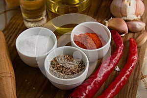 Close-up of different spices, such as paprika powder, garlic heads, salt, red pepper, oil