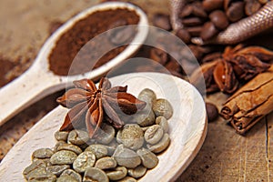 Close-up different types of coffee beans on wooden spoons, green coffee, sticks of cinnamon and anise star, macro, set