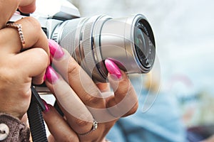 Close-up of a digital camera being used by a woman with painted fingernails
