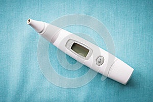 Close-up of digital ear thermometer on sold blue background with copy space