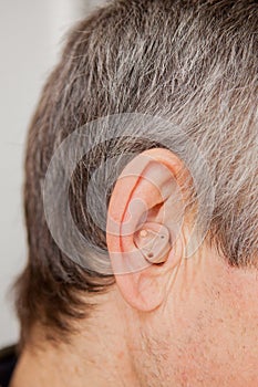Close-up Digital modern hearing aid in the ear of aged old man