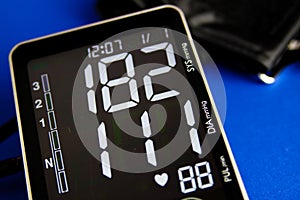 Close up of digital sphygmomanometer monitor with cuff showing high diastolic and systolic blood pressure photo