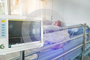 Close up digital vital signs of measuring heart and blood pressure monitor with elderly patient sleep on the bed