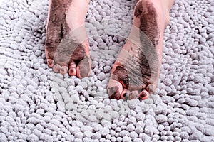 Close up of dirty bare feet of child on gray mat