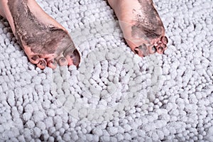 Close up of dirty bare feet of child on gray mat