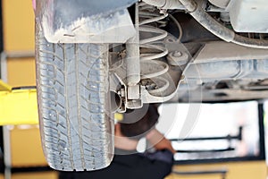 Close up dirty car shock absorber with blurred technician in service shop