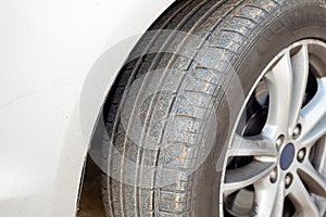 Close up of dirty car wheel with rubber covered rubber tire