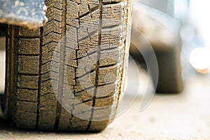 Close up of dirty car wheel with rubber tire covered with yellow mud