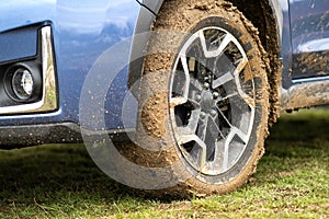 Close up of dirty car wheel with rubber tire covered with yellow mud