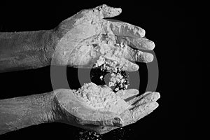 Close up dirty cook hands with dough, flour. Against dark background