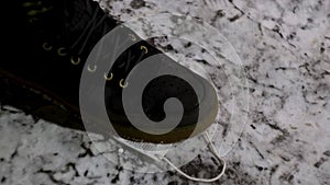 Close up of dirty discarded medical face mask lying on snowy ground. Concept. Male boot stepping on a white face mask