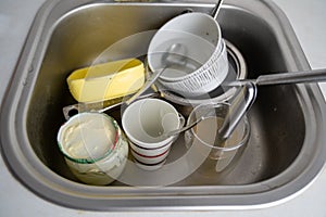 close up of dirty dishes in kitchen sink, pile of utensils need wash, a lot of tableware