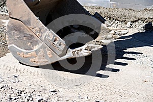 Close up dirty excavator scoop at road construction site