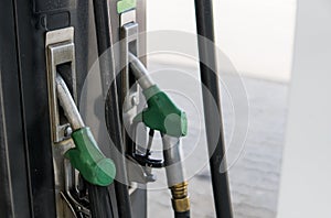 Close up on dirty fuel nozzle in oil dispenser with gasoline and diesel in service gas station. Pattern petrol pump gun