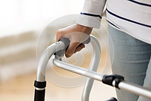 Close up disabled older woman holding hand on walker