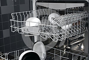 Close-up of dishwasher drawers, with black and white plates on dark kitchen background
