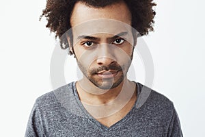 Close up of displeased african man looking at camera brutally. White background.