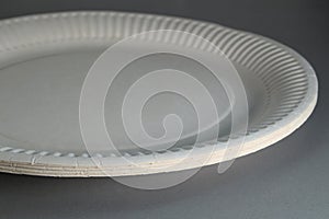 Close-up of disposable white paper plates on table. Soft focus
