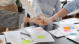 Close up diverse colleagues employees team fists bumping at meeting