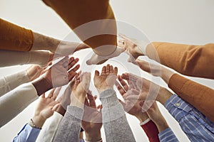 Close up diverse colleagues joining hands giving high five view from bottom