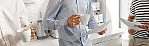 Close up of diverse coworkers drink coffee during break and talking about work project