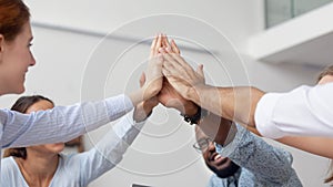 Close up diverse employees team giving high five at company meeting