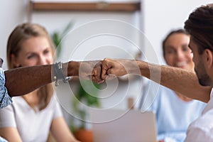 Close up diverse male hands, colleagues giving fist bump