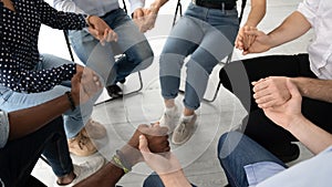 Close up diverse patients sitting in circle, holding hands