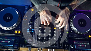 Close-up of a dj hands using mixer and turntables in nightclub.