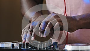 Close-up Dj mixer controller desk in club musician studio home disco party old African male hands touching buttons
