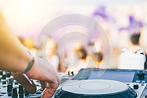 Close up of DJ`s hand playing music at turntable on a beach party festival - Portrait of DJ mixer audio in a beach club photo