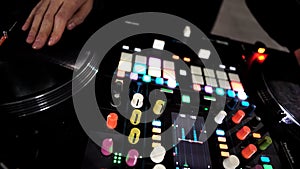 Close up of DJ using a modern sound mixer for playing electro music at the nightclub. Art. Colorful Buttons and vinyl