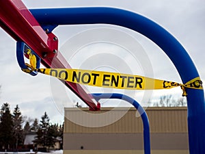 Close up of â€œDo Not Enterâ€ Caution Tape on playground equipment due to Covid 19 Pandemic