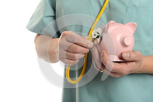 Close up of Doctoc with stethoscope and piggy bank