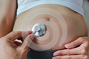 Close-up Doctor attentively listening pregnant woman`s belly