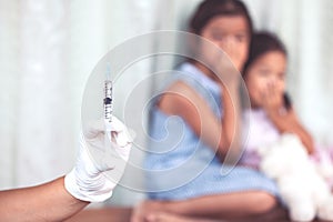 Close up doctor hand holding syringe with a child girl fear