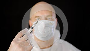 Close up doctor hand in protective glove holding syringe with injection isolated on black background. Medical worker in