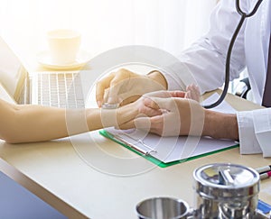 Close up of doctor hand reassuring her female patient at hospital. Closeup hands of medical doctor carefully holding patient