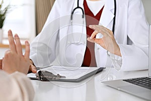 Close up of a doctor hand showing ok sign while phusician and his patient discussing medical records after health