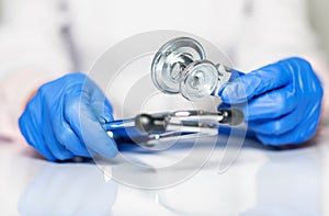 Close up of doctor hands in gloves with stethoscope, medical exam concept