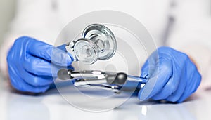 Close up of doctor hands in gloves with stethoscope, medical exam concept