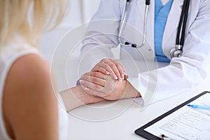 Close up of doctor hands reassuring her female patient