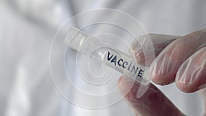 Close up doctor hands showing ampoule with vaccine inscription. Plastic ampoule with antiviral vaccine in hands medical