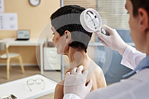 Close up of doctor holding magnifying glass examining head of female patient