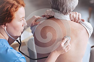 Close up of doctor listening back of patient with stethoscope