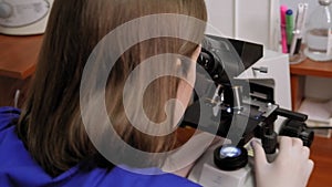 Close-up of a doctor looking through a microscope in a laboratory or hospital.