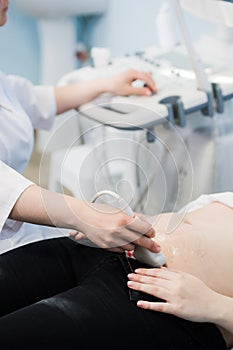 Close-up Of Doctor Moving Ultrasound Probe On Pregnant Woman`s Stomach In Hospital