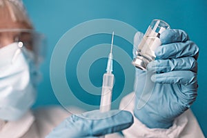 Close up of doctor or nurse holding viol with vaccine against corona virus, taking covid vaccination booster shot or 3rd